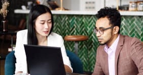 Image of male and female investors looking at laptop screen