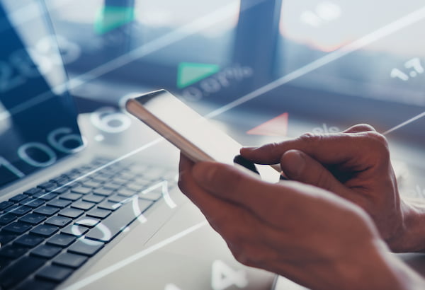 Smartphone user with financial figures in the background